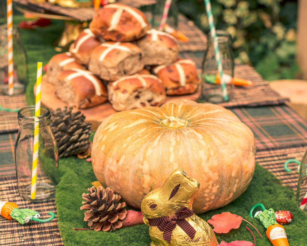 Kids Easter Party Table for Autumn Easter Egg Hunt. Decorated with pumpkins, pine cones and hot cross buns.