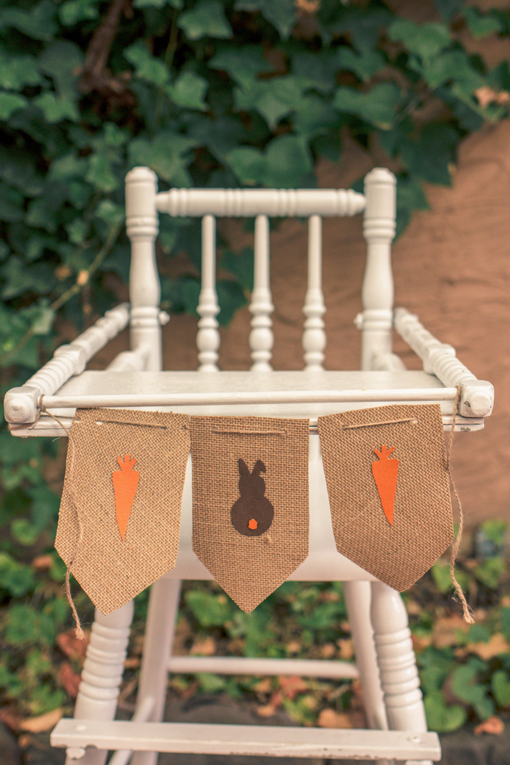 Vintage painted baby high chair decorated for autumn easter egg hunt with bunting of carrots and easter bunny