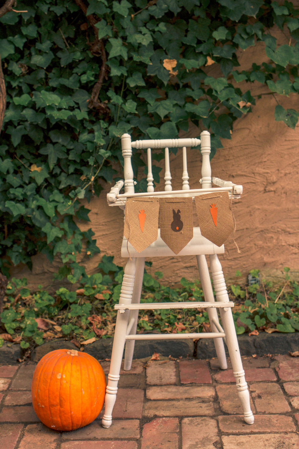 Vintage painted baby high chair decorated for autumn easter egg hunt with bunting, carrots and pumpkins