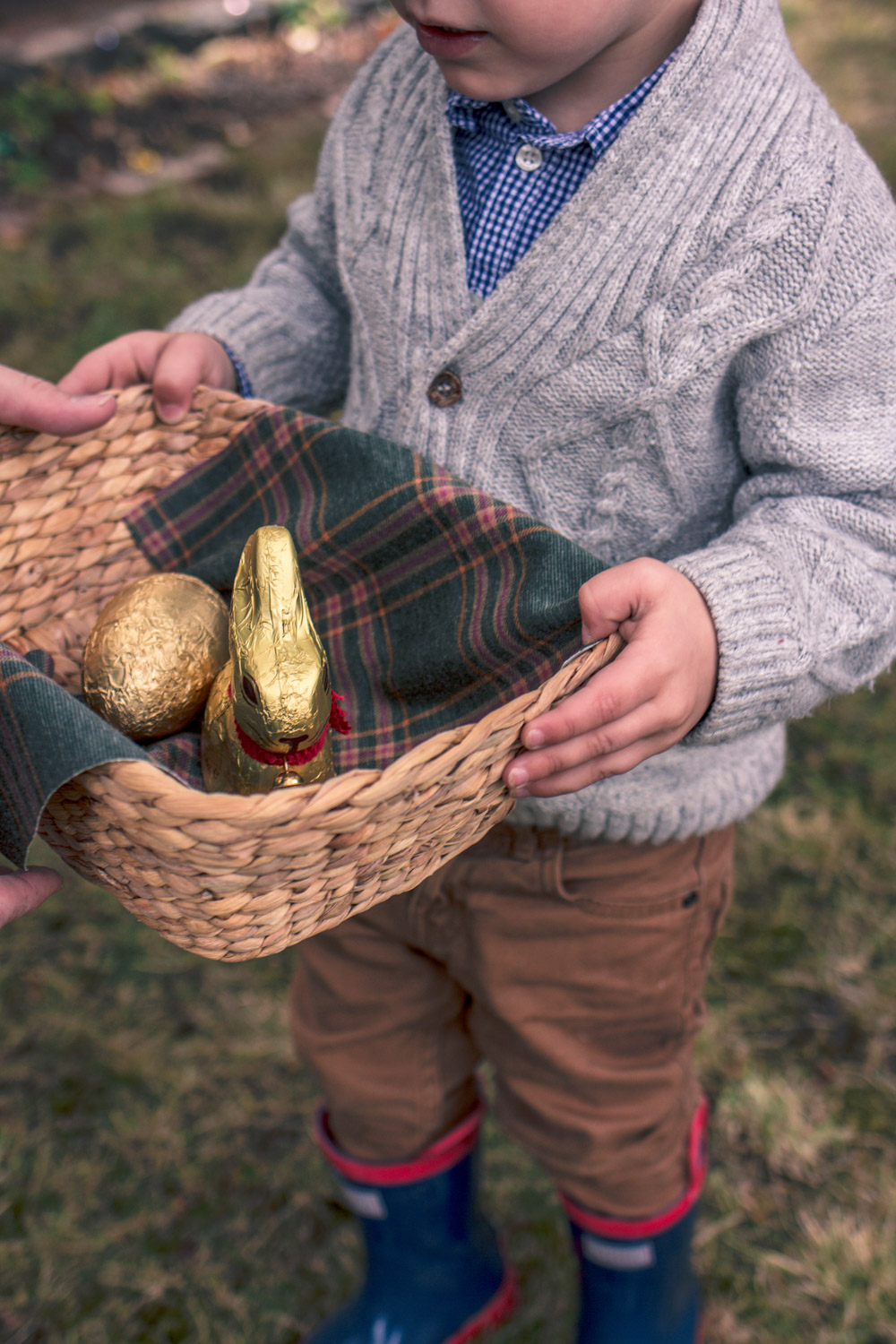 Little boy in vintage knitwear holding a basket of chocolates at Goldfields Girl Autumn Easter Egg Hunt