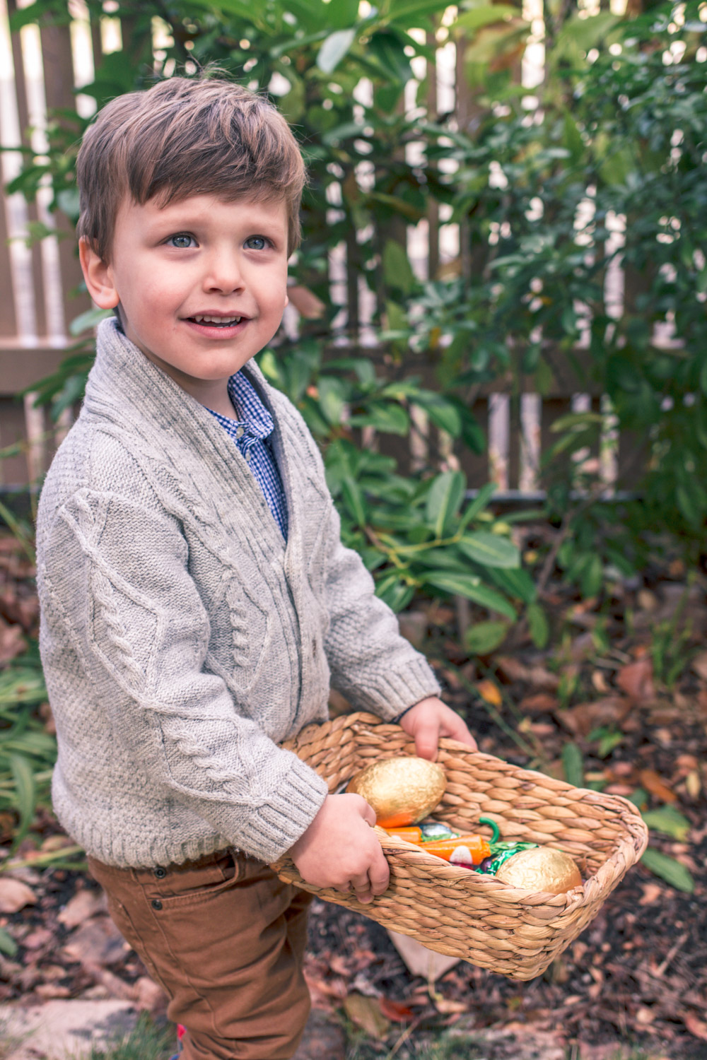 Toddler wearing Janie and Jack Knit Cardigan at Autumn Easter Egg Hunt holding a basket of chocolate eggs and carrots