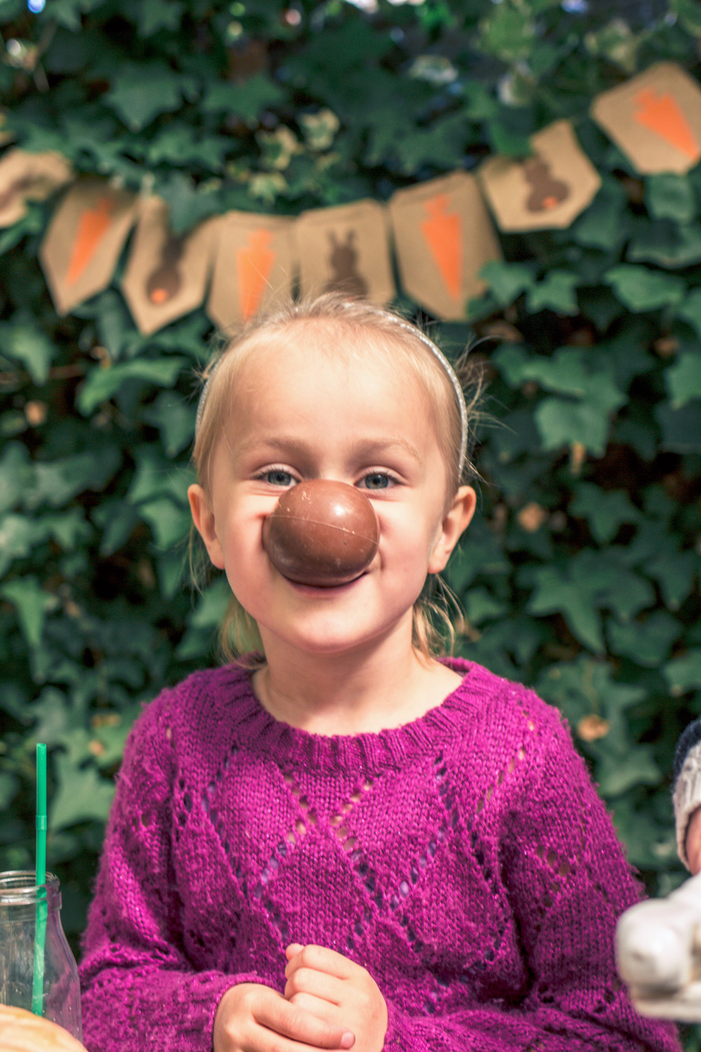 Little girl eating a chocolate easter egg at autumn easter egg hunt