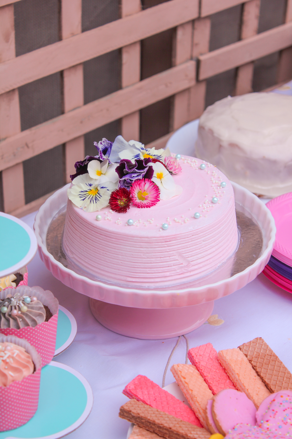 Pink birthday cake decorated with fresh spring flowers