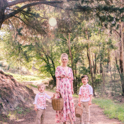 Goldfields Girl wearing romantic silk floral dress walking along forest trail with little boys all holding berry baskets