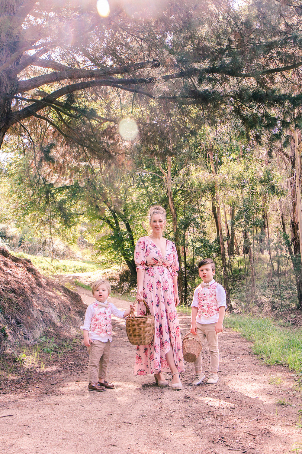 Goldfields Girl wearing romantic silk floral dress walking along forest trail with little boys all holding berry baskets