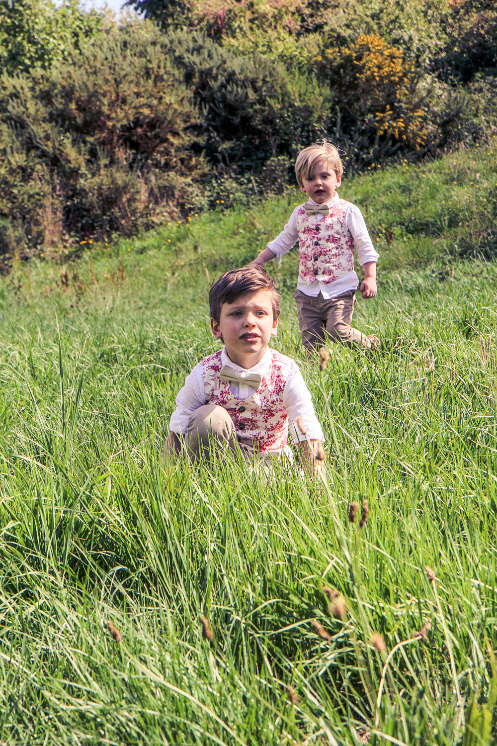 Little boys wearing matching bow ties and Janie and Jack red toile vests