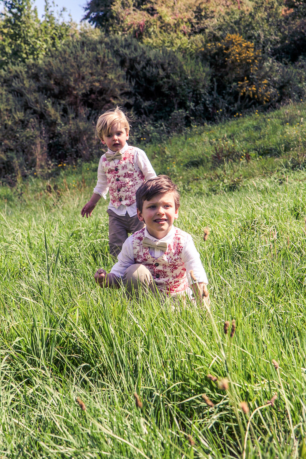 Little boys wearing matching bow ties and Janie and Jack red toile vests