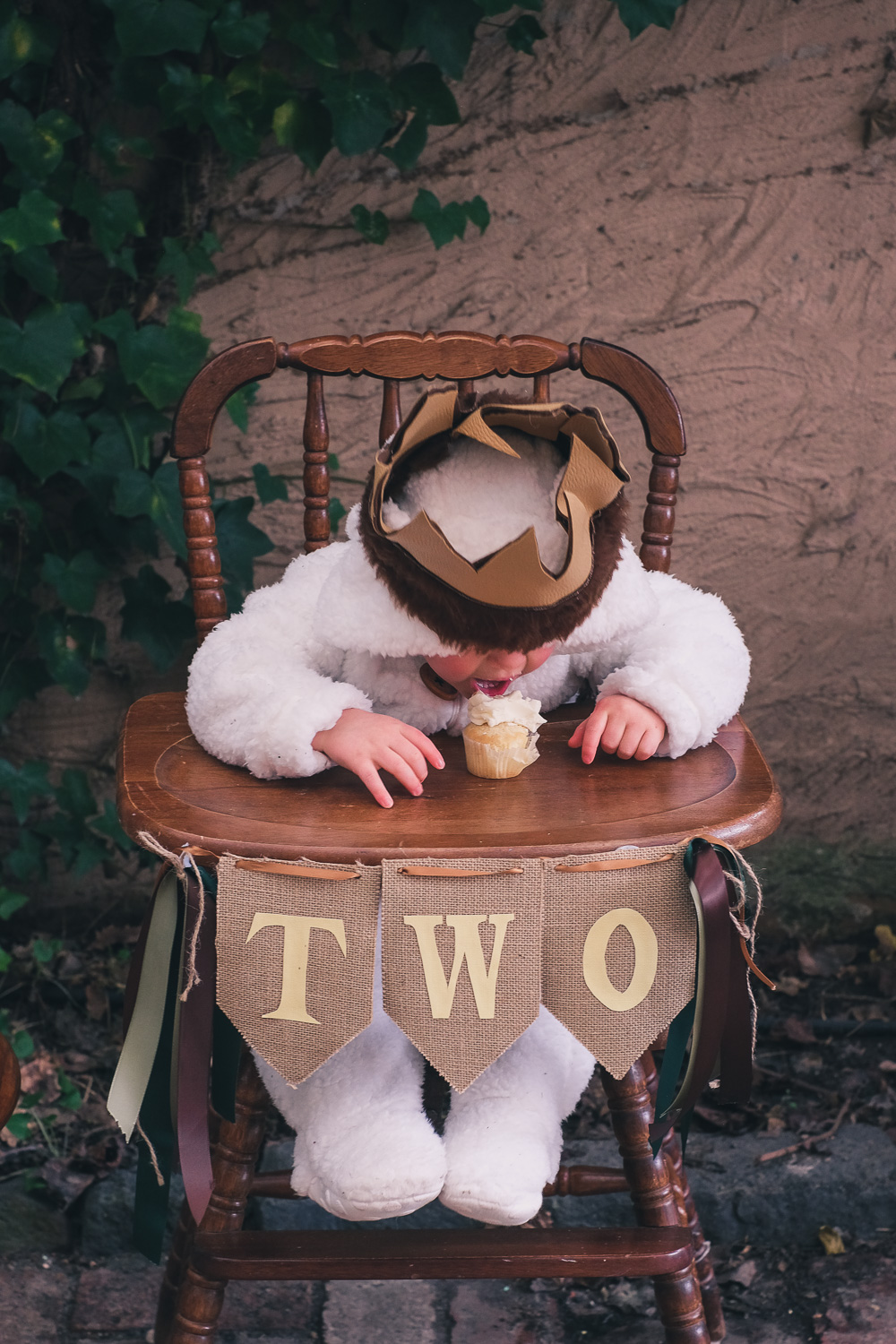 Child wearing Where The Wild Things Are party costume sits in a vintage high chair