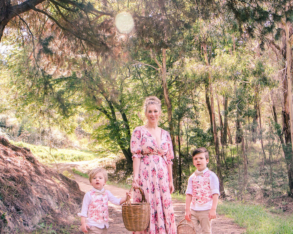 Goldfields Girl wearing romantic silk floral dress walking along forest trail with little boys all holding berry baskets